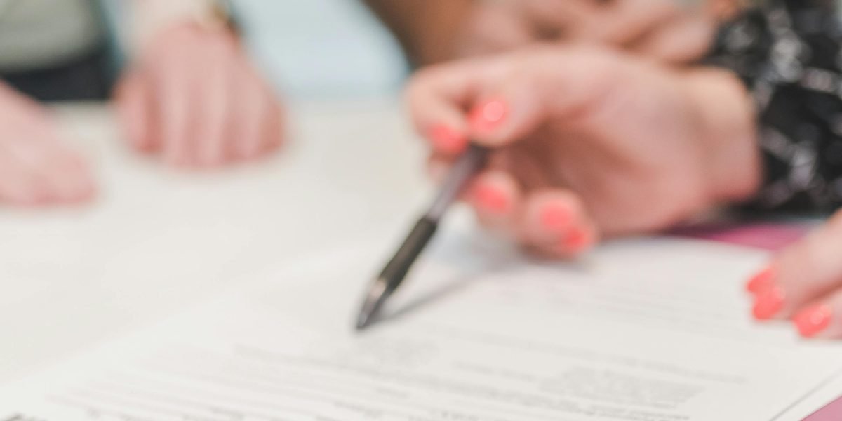 The moment of commitment, as an individual signs important paperwork for a property purchase.