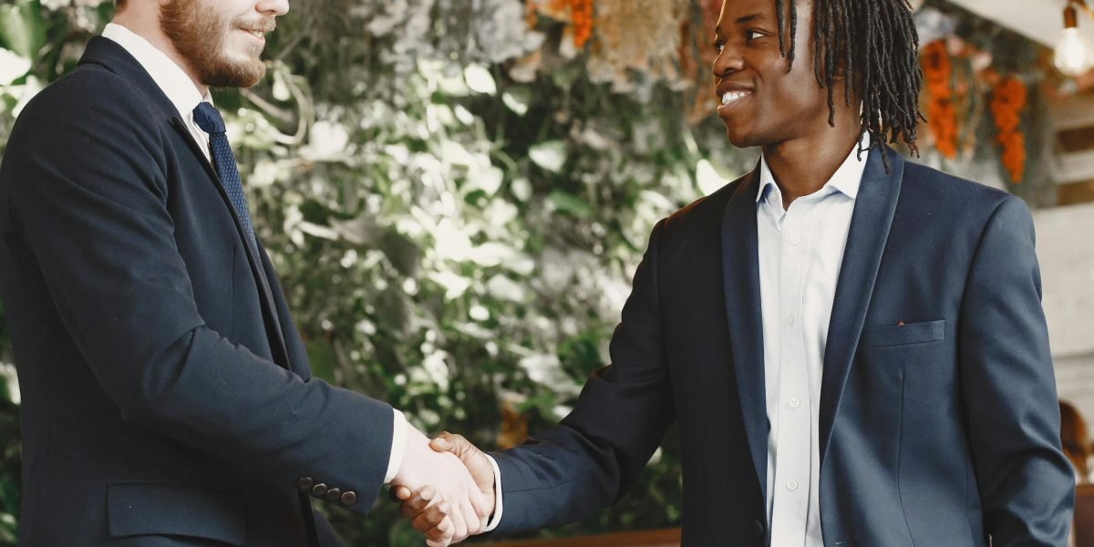 Two business professionals shake hands at a networking event, signaling a successful connection or partnership.