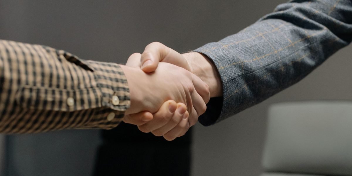 Two professionals shaking hands, symbolizing trust and successful partnership in a business context.