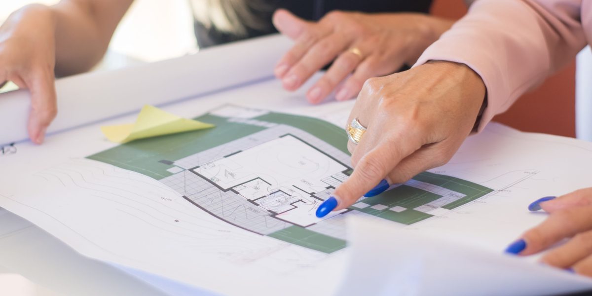 A diverse team collaborating around a table with a large urban development plan, representing the scale and planning of Wasl's portfolio.