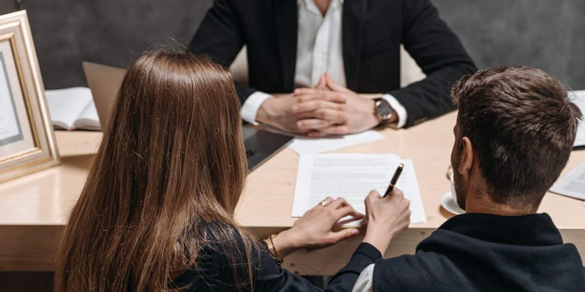 A professional couple carefully reviewing legal documents with an advisor, emphasizing the importance of due diligence.